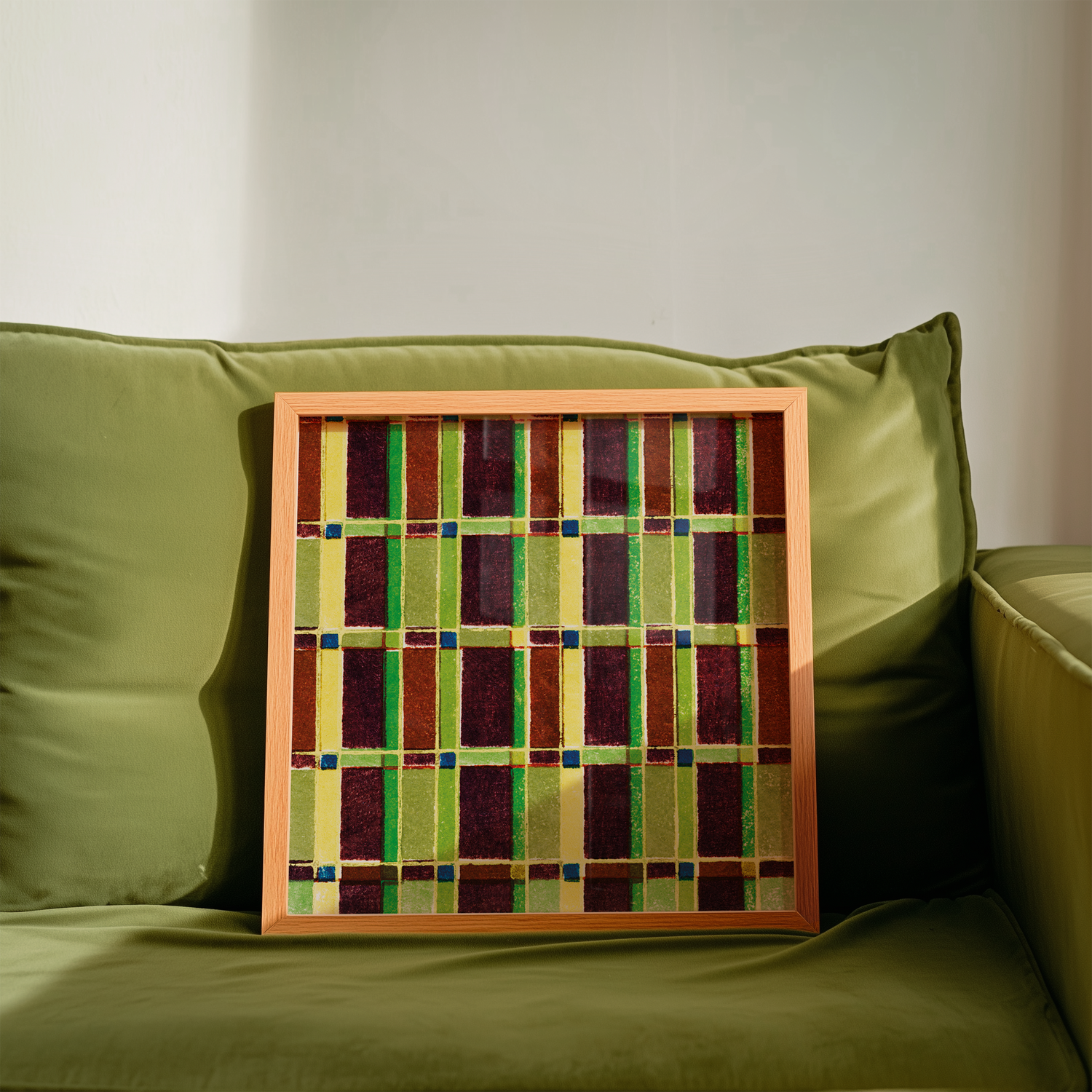 Image of a framed vintage poster with geometric abstract pattern in green, red and blue, placed on a green sofa – poster tavla med träram, modern konst för inredning från Posterton.